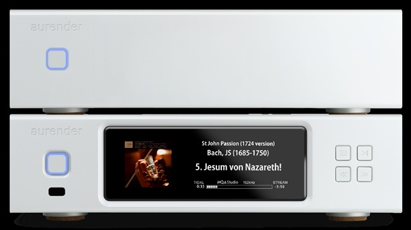 Two white Aurender audio components stacked; the lower unit's touchscreen shows a Bach track, 'Jesu m von Nazareth', with playback controls on the right.