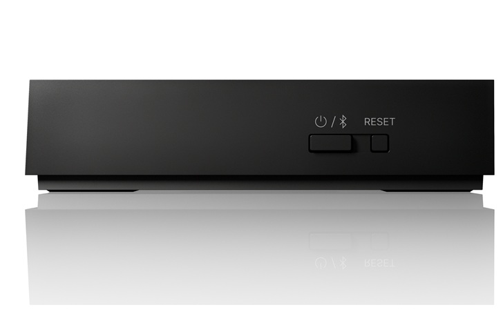 Black rectangular electronic box with a power/Bluetooth icon and a RESET button on the front, shown on a reflective surface.